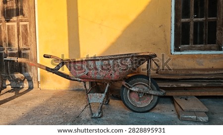 Old Rusty Wheelbarrow in Front of a Rustic House
