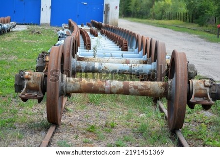 Old rusty wheels of railroad train carriages. Axles.