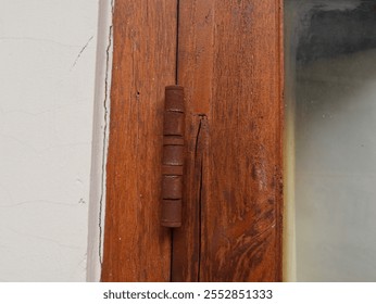 an old and rusty window hinge due to exposure to rainwater in tropical Indonesia, corrosion on exposed metal