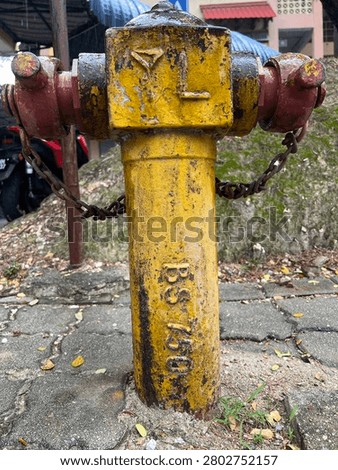 Old rusty yellow fire hydrant with peeling paint on a concrete pavement sidewalk.