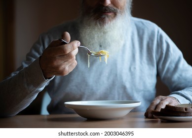 Old Sad Man With A Long Gray Beard Sitting By The Table And Eating Soup And Bread