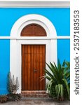 Old San Juan Charming Wooden Door with Blue Wall and Green Plants Capturing The Vibrant Spirit Of Puerto Rico.