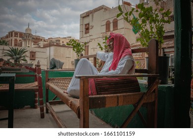 An Old Saudi Man Sits On A Balcony In The Old City Of Jeddah, Saudi Arabia 2020