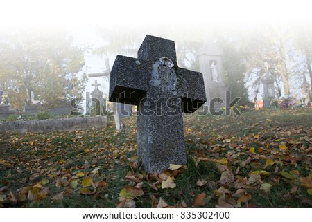 Old scary graves in the cemetery. Spooky tomb stones in a foggy autumn scene in the graveyard. All Saints Day / All Hallows / 1st November. Slovakia