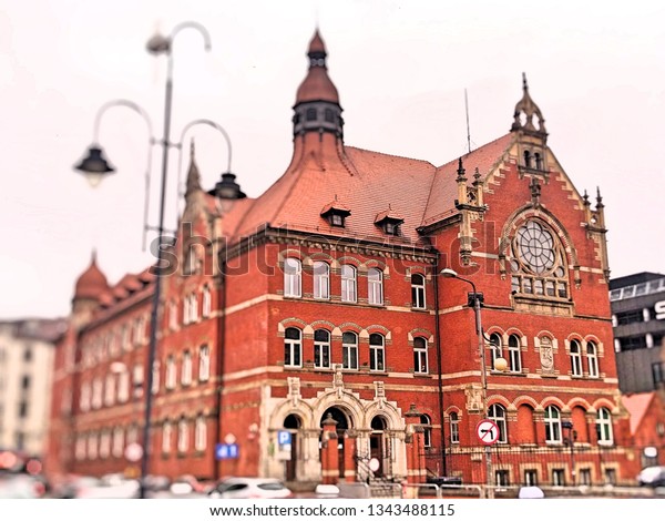 
An old school building or a red
brick museum next to a busy street with cars in the
city