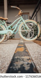 Old School Classic Teal Bike Sitting On A Rusty Bike Rack With Another Bike In The Background.