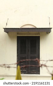 Old School Window Made Of Black Wood With A Blur Foreground Iron Fence And Barbed Wire