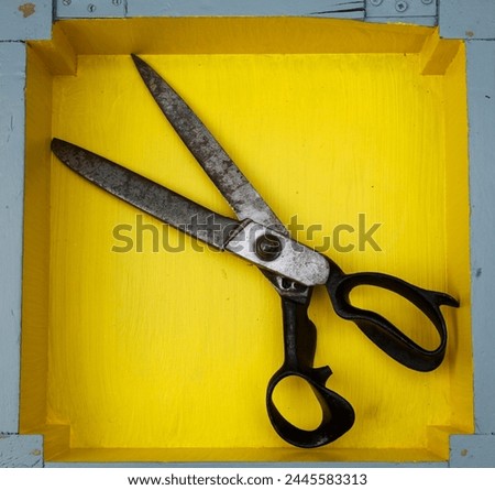 Old scissors on a yellow background. Vintage style. Top view.