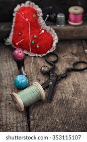 Old scissors,spools of thread,buttons and beads on wooden table