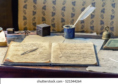 Old scribbled Notepad lying on the table, on the background of inkwell with a feather and other documents.