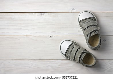 Old Secondhand Black Canvas Shoes Or Sneakers For Kids Or Baby Foot On Vintage White Wood Floor Or Table Top View With Copyspace