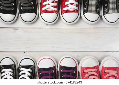 Old Or Secondhand Many Canvas Shoes Or Sneakers Red Pink Purple Black Scott Color For Kids Or Baby Foot On Vintage White Wood Floor Or Table Top View With Copyspace