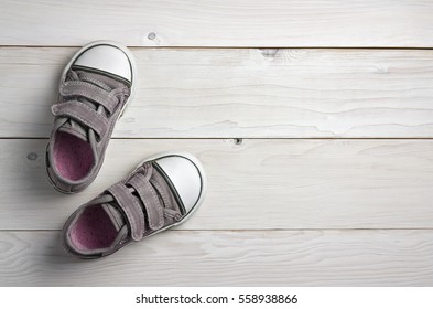 Old Secondhand Pink With Black Canvas Shoes Or Sneakers For Kids Or Baby Foot On Vintage White Wood Floor Or Table Top View With Copyspace