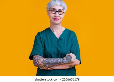 old senior asian female professional doctor grey hair and tattoo with glasses wear hospital uniform standing with confident and cheerful expression studio shot yellow background - Powered by Shutterstock