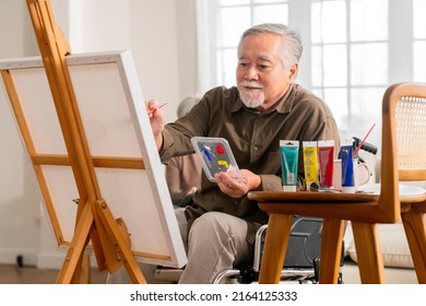 Old Senior Asian Male Using Art Therapy While His Legs Is Injured At Home,asian Elder Man Spend Recovering Of His Leg Is Getting Better With Painting Canvas Art In Living Room At Home