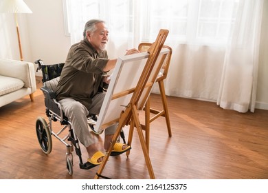 Old Senior Asian Male Using Art Therapy While His Legs Is Injured At Home,asian Elder Man Spend Recovering Of His Leg Is Getting Better With Painting Canvas Art In Living Room At Home