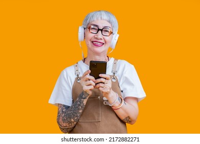 Old Senior Asian Woman Wear Apron Hand Choosing Music Playlist From Smartphone Relax Casual Lifestyle,asia Tattoo Woman Wear Headphone Listen Music Carefree Isolate Yellow Background Studio Shot