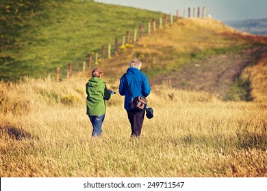 Old Senior Citizen Couple Taking A Walk In The Field In Ireland. Post Processed With Vintage Filter. 