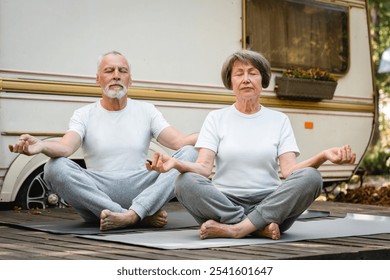 Old senior elderly couple athletes eco-tourists meditating sitting in lotus position, doing yoga serenity while traveling together in camper van trailer motor wheel home - Powered by Shutterstock