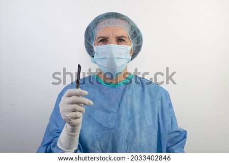 old senior female woman surgeon stand white background uniform doctor health  care emergency profession help people hand hold scalpel medical gloves surgical hair net