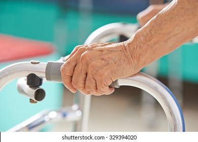 Old Senior Hands Holding On To A Walker For Support