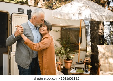 Old senior happy couple spouses dancing, spending romantic date together while on holiday in camper van, caravanning by trailer motor home - Powered by Shutterstock