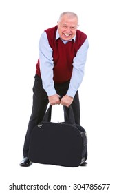 Old Senior Man In Cardigan Color Marsala And Shirt, Holding A Very Heavy Suitcase In Two Hands Between His Legs, Clenched White Teeth, Isolated White Background, Human Emotions And Facial Expressions