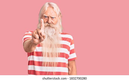 Old senior man with grey hair and long beard wearing striped tshirt pointing with finger up and angry expression, showing no gesture 
