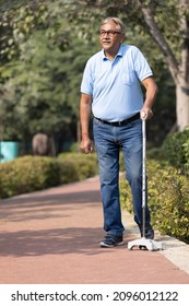 Old senior man holding walking stick at park