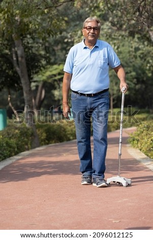 Old senior man holding walking stick at park