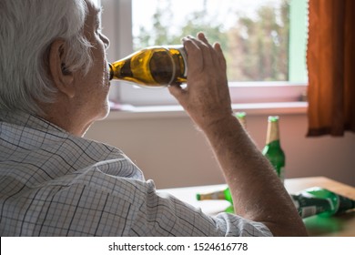 old senior man sit next to table drink alcohol bottle at home sad alone alcoholism - Powered by Shutterstock