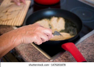 Old Senior And Mature Woman Is Cooking And Preparing Fish Or Something At The Kitchen At Home - Alone And Siolated