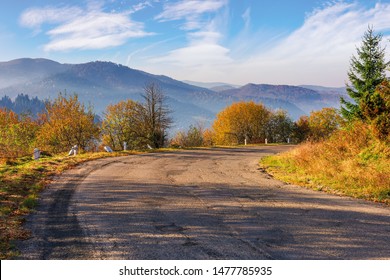 old serpentine road in mountains. beautiful autumn scenery in morning misty light. wonderful october weather with fluffy clouds on the sky. ridge in the distance - Powered by Shutterstock