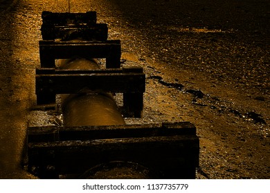 Old Sewage Pipe With  Protecting Wooden Brackets Attached On The Beach In Uk Coastal Area During Sunset.Dark Industrial  Abstract.