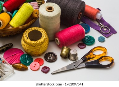 Old sewing accessories for sewing handmade on a white background, a spool of thread, scissors, buttons. A set for needlework. View from above