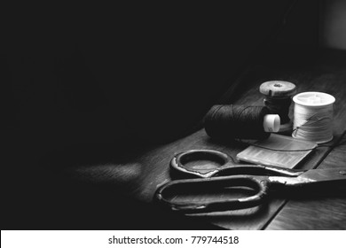 Old sewing machine needle with black thread, on a old grungy work table. Tailor's work table. textile or fine cloth making. industrial fabric, darck background black and white - Shutterstock ID 779744518