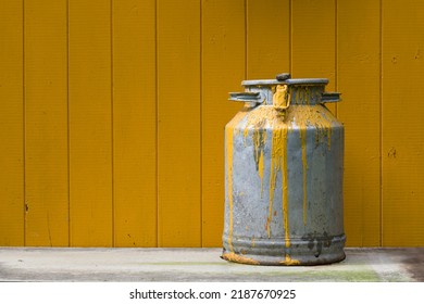 Old and shabby can with yellow paint. Can with paint in front of plank wall painted in the same yellow color.