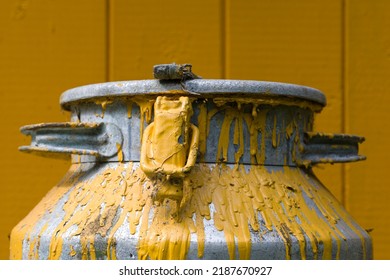 Old and shabby can with yellow paint. Can with paint in front of plank wall painted in the same yellow color.