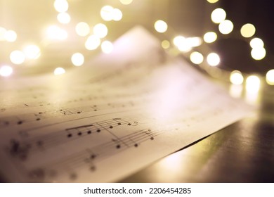 Old sheet with Christmas music notes as background, bokeh effect
