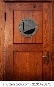 Old Ship Wooden Door With Porthole. Vintage Sailing Boat Crew Cabin Entrance With Round Window. Beautiful Sea And Yacht Concept Backdrop. Vertical, Close Up, Copy Space