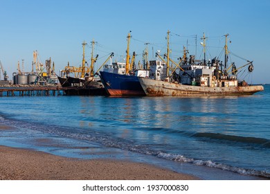 Old ships at the pier on the sea with an empty beach with clear blue water and sky. Seaport on the shore with cranes and boats. Wallpaper for desktop, poster, marine travel photo for post card design. - Shutterstock ID 1937000830
