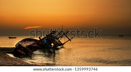 Old shipwreck boat on beach, broken fishing ship lies on side the shore with silhouette sunset background landscape scene. wrecked ship at Hat Krathing Lai Seashore Park. Sukhumvit Pattaya, Thailand
