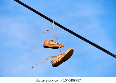 Old Shoes hanging on electrical wire against a sky. Shoe tossing
