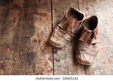 Old Shoes On Wooden Floor. Pair Of Old Dirty Brown Leather Shoes.