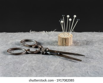 Old Siccors With Pins, Work Table. Textile Or Fine Cloth Making On Black Background.