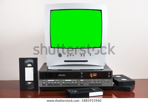 Old silver green screen TV for video and\
photos with built-in DVD player and a vintage video recorder from\
the 1980s, 1990s, 2000s next to\
it.