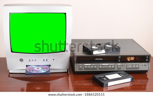 Old silver green screen TV for video and
photos with built-in DVD player and a vintage video recorder from
the 1980s, 1990s, 2000s next to
it.