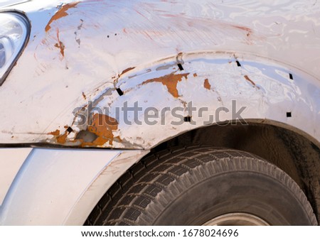 Old silver painted car needs a refurbishment due to rusty holes in the metal of the car wing