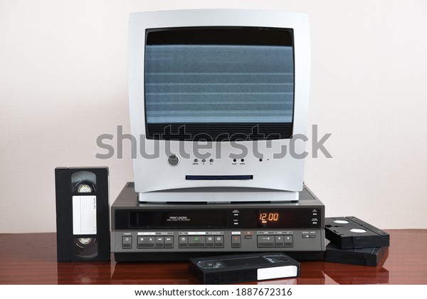 Old silver TV with noise and interference on\
screen with built-in DVD player and vintage video recorder from\
1980s, 1990s, 2000s.