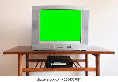 Old Silver Vintage TV With Clutter From 1980s, 1990s, 2000s, VCR On Wallpaper Background.